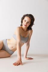 Fototapeta premium Young sensual woman with well-kept skin in underwear posing isolated on gray studio background. Spa, fashion, beauty and skin care concept