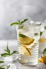Lemonade or mojito cocktail with lemon and mint, summer iced refreshing drink on gray background
