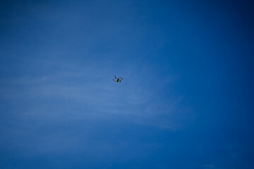 A flying drone rose high into the sky, a quadcopter against the blue sky, a flying car for photo shooting.
