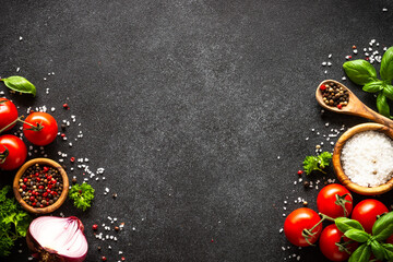 Food background on black stone table. Fresh vegetables, herbs and spices. Ingredients for cooking with copy space.
