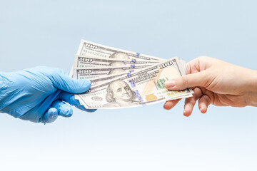 A hand in blue surgica glove takes the money (dollars). corruption in medicine field. Corruption
