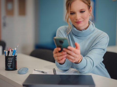 Business woman working in office. Online business, young professional in workplace. communicating with colleagues via messenger on smartphone, or using apps. Female entrepreneur sending text message.