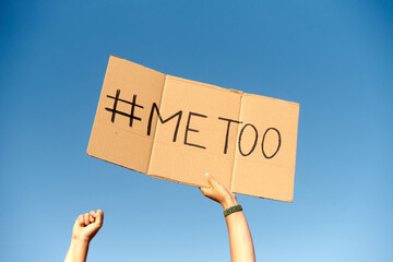 Two woman's hands holding a cardboard sign that says me too No sexism concept.