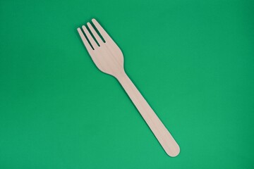 Wooden biodegradable fork in a green background concept of ecological environment .
