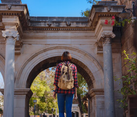 travel to Turkey. Happy asian female tourist traveller with backpack walks in old city. Woman against backdrop of Hadrian's gate - popular attraction in old city of Antalya
