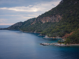 travel to Lagoon in Oludeniz, Fethiye, Turkey. beach near Darbogaz. Winter landscape with mountains, green forest, azure water, beach and cloudy sky