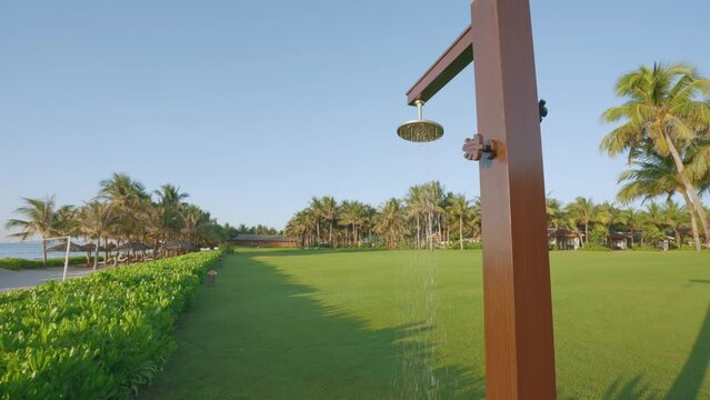 A faucet for tourists to shower after swimming on the beach in a beautiful landscape at a tropical resort with a wide-angle view.
