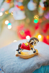 Christbaumschmuck Schaukelpferd mit Christbaum und Weihnachtsbeleuchtung im Hintergrund