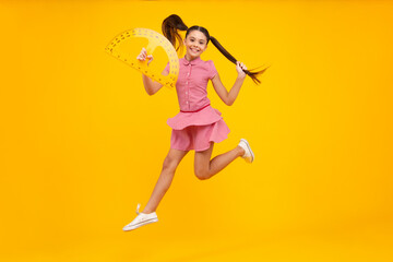 Measuring school equipment. Schoolgirl holding measure for geometry lesson, isolated on yellow background. Student study math. Happy teenager, positive and smiling emotions of school girl.