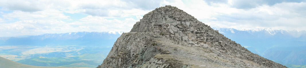 Dramatic panoramic landscape of rocky mountains among the clouds, banner format