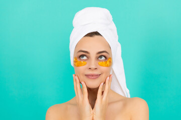 young woman smile has collagen gold eye patches on face with towel