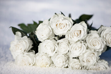 A bouquet of white roses lies on the snow.
