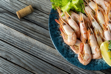 Boiled shrimps on a wooden background, lemon. Macro