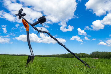 Metal detector. Electronic device with metal detecting sensor. Shovel and metal detector on grass....