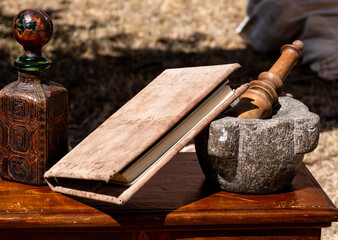 stone mortar and pestle on a wooden table with a book - obrazy, fototapety, plakaty