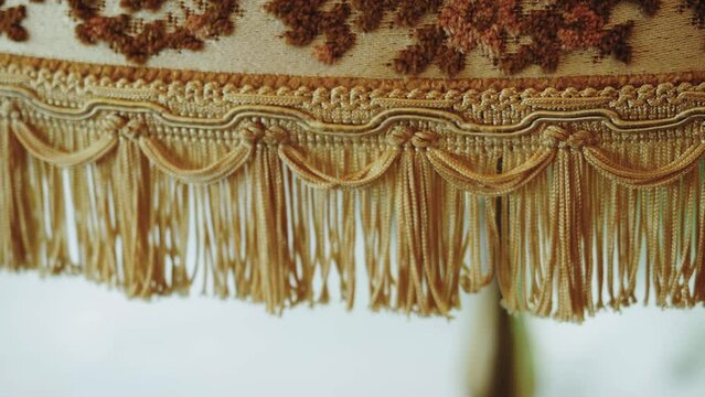 Close-up vintage style floor lamp torchere with bell shape fringed drapery shade being switched on and off by pulling a chain, slow motion, texture.