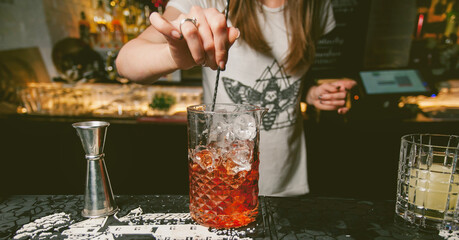 The girl bartender prepares a cocktail in the nightclub. Barmaid preparing cocktails in a bar for her clients - Bartender at work in a club. Bartender making alcoholic cocktail. photo vintage toning