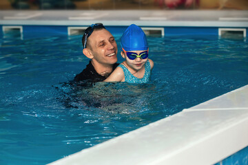 a swimming coach conducts an individual lesson in the pool with a child. the concept of healthy and sports leisure of children