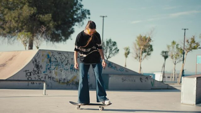 Young woman skateboarding, carving the bowl at the park. Girl rides a skateboarding in a skate park at summer. Tracking shot. High quality 4k footage