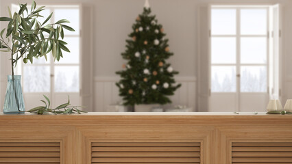 Wooden table top, cabinet, panel or shelf with shutters close up. Olive branch in vase and candles. Blurred background with white modern Christmas living room, interior design