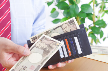 財布から一万円札を取り出すワイシャツ姿の男性