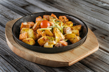 Grilled potatoes with pieces of salmon on a pan. Sprinkled with ukropchik.