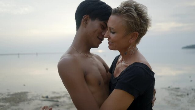 Interracial Couple With Age Differences Kissing And Hugging Each Other On Sunset Beach At Sunset - Bust Slow Motion