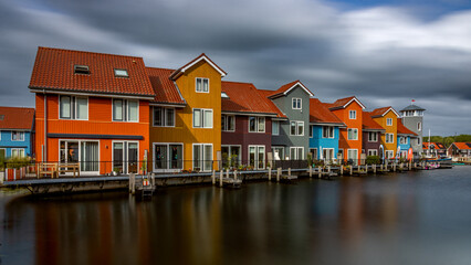 Fototapeta na wymiar The colorful houses in Reitdiephaven in Groningen Netherlands as a long exposure with smooth water and moving clouds