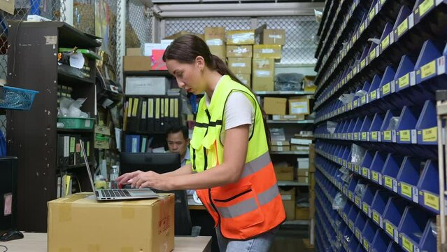 Warehouse Manager and female warehouse clerk counting the small parts stored in the blue storage compartment. to check the balance to prepare for the next order