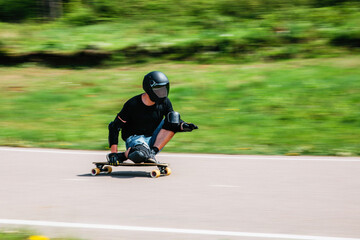 Young sporty man on a longboard rides at high speed down the track