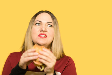 A hungry woman is biting a big tasty burger