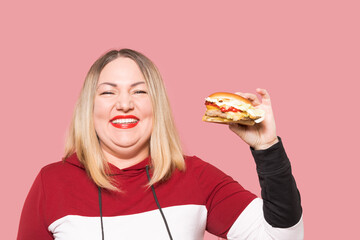 Body positive Cheerful woman with appetite looks at a delicious burger. . Unhealthy food.