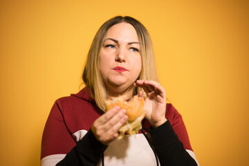 A hungry woman is biting a big tasty burger