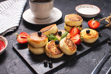 Cottage cheese pancakes, ricotta fritters or syrniki with currant and strawberries. Healthy and delicious breakfast