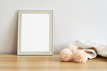 Blank picture frame mockup on white wall and pink flowers. View of modern style interior with artwork mock up on wall. Home staging and minimalism background                                          