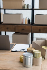canned food and clipboard near laptop on desk in charity center.