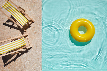 Top view swimming pool with yellow chaise lounge and swimming ring. Summer vacation concept.