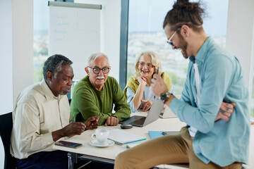 A group of senior students sit in a classroom with their teacher and work on a school project.
