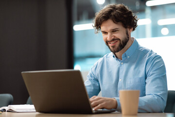Handsome mature businessman working with laptop pc at his desk in office, blank space