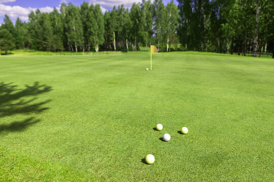 the photo of golf balls near hole on fairway with the green background
