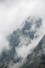 mystical photo of rough rocky mountains surrounded by a white blanket of clouds