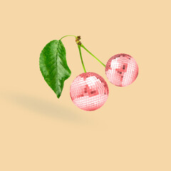 Unusual combination of usual things. Red cherries as a disco balls flying on beige background....