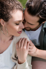 portrait of bearded man and curly woman hugging with closed eyes.