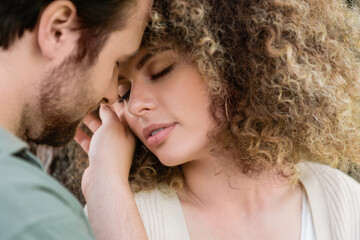 portrait of young man touching face of curly and pretty woman.