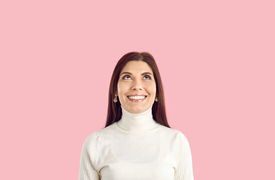 Happy Young Woman In White Turtleneck Standing Isolated On Pink Background, Looking Up, Smiling, Dreaming Of Present, Imagining Something Nice, Thinking About Holidays, Choosing Between Two Options