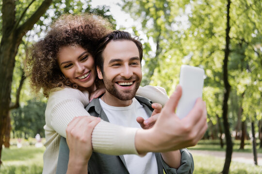 happy young couple taking selfie on blurred smartphone in summer park.