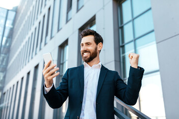 Happy glad excited european millennial bearded businessman in suit rejoices to successful deal or celebrate victory