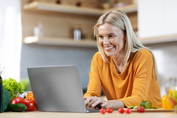 Pretty blonde woman reading food blog and cooking at home
