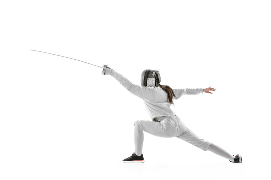 Dynamic portrait of female fencer in sports costume with rapier in hand training isolated on white background. Sport, youth, healthy lifestyle, achievements.