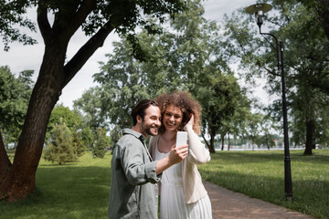 positive young couple taking selfie on smartphone in summer park.